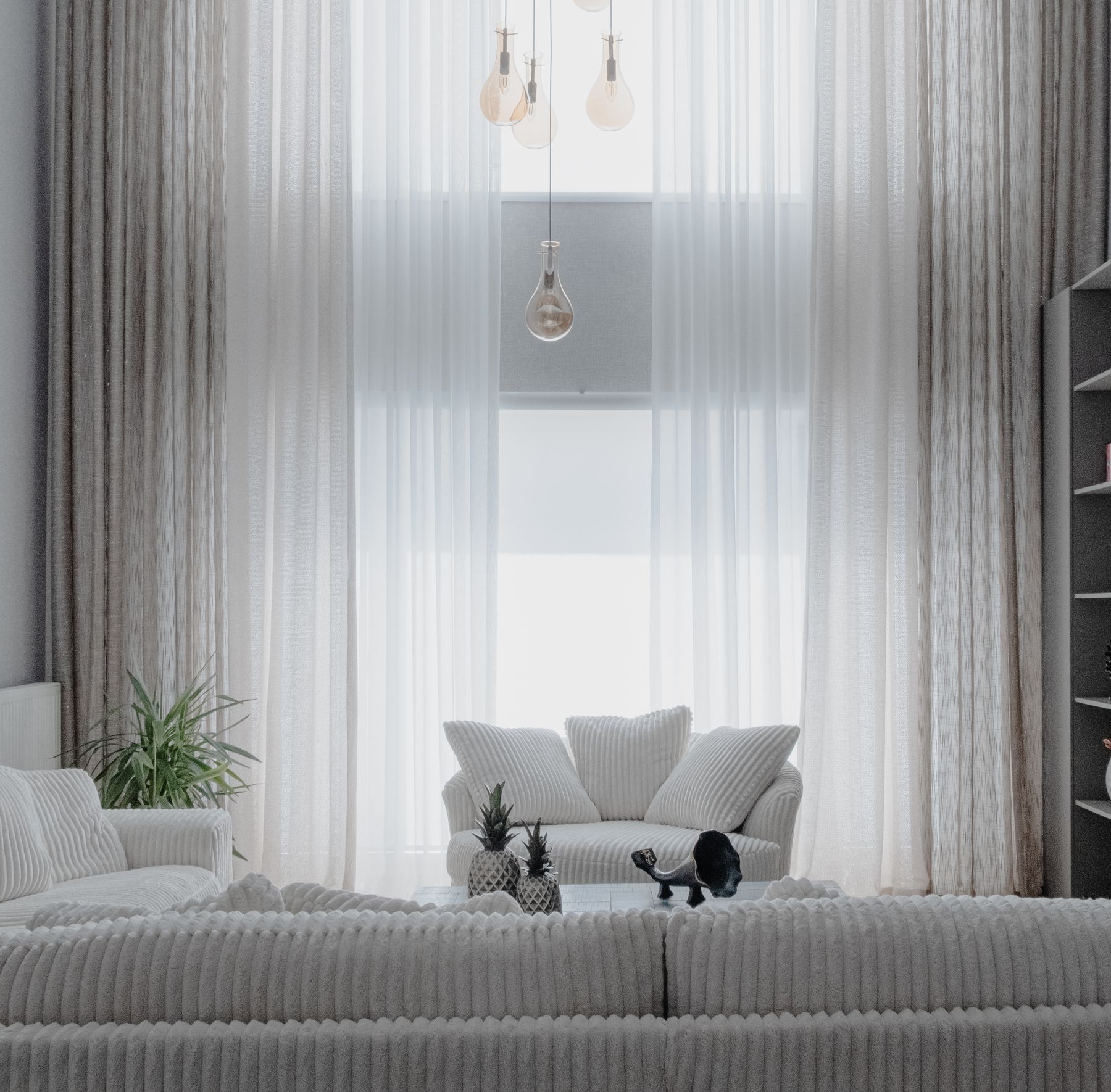 Bright, freshly cleaned South Florida living room with sheer curtains, a light sofa, and tropical greenery